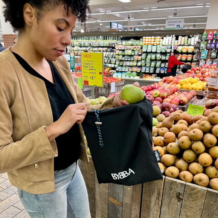 Packable, foldable, reusable bag made from recycled ocean plastic by BYBBA, used for grocery shopping.