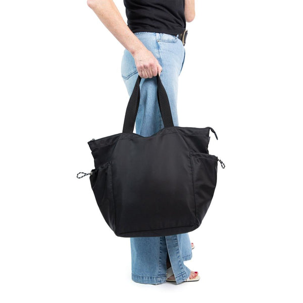 Person holds full, large black tote at their side