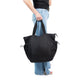 Person holds full, large black tote at their side