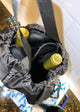 top view of hanging large black bag holding two bottles in a space with white titled walls