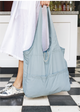 Misty Blue Bag held at person's feet amongst large checkered floor