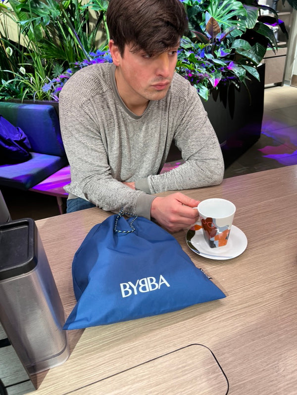 guy sitting with coffee and blue pouch on top table