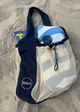 net bag in the sad at the beach holding a towel, glasses, and a magazine