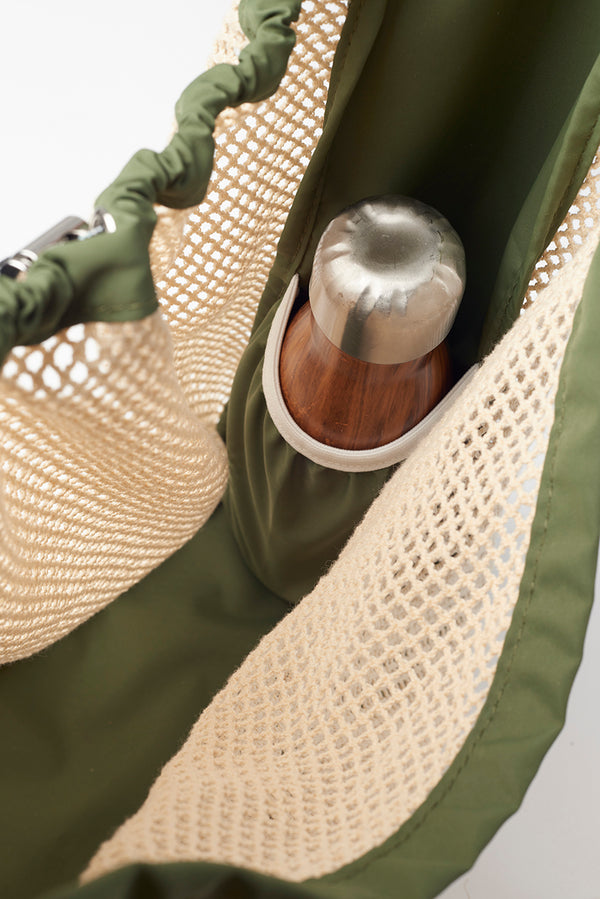 inside view of net bag with water bottle pocket holding a water bottle