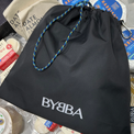 Black BYBBA drawstring bag, packable, foldable, reusable, made from recycled ocean plastic, with blue-yellow rope handle.