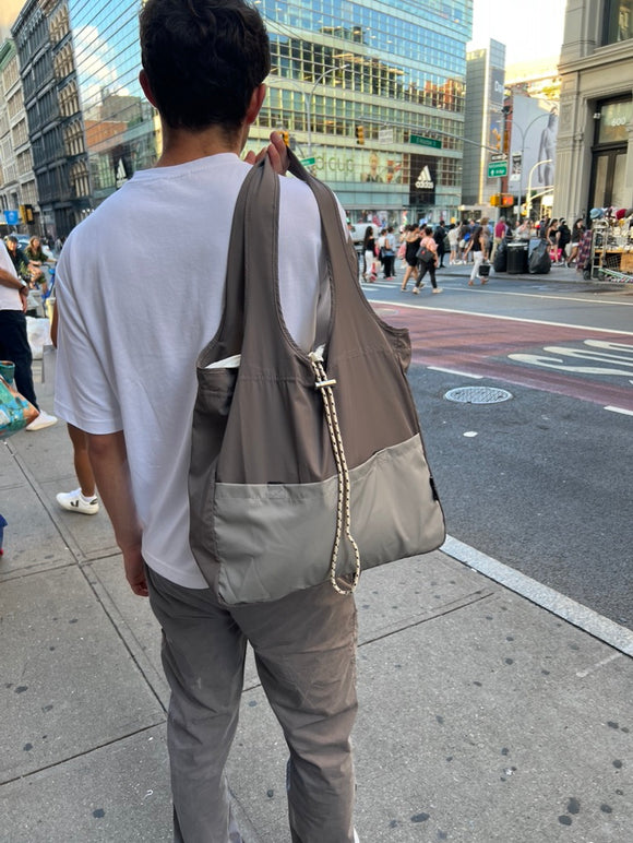 man in urban setting holding dolphin bag over shoulder