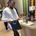 Man holding black BYBBA packable, foldable, reusable bag made from recycled ocean plastic at store counter