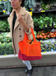 person in a produce section holding an orange bag