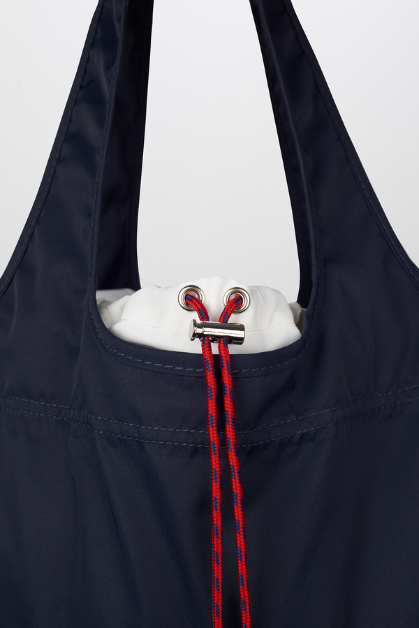 Red cord closure on navy blue tote bag